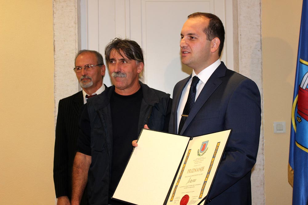 Valerio Bračanov iz ruku načelnika Ivana Klarina preuzima priznanje za MNK Jezera (Foto; Općina Tisno)