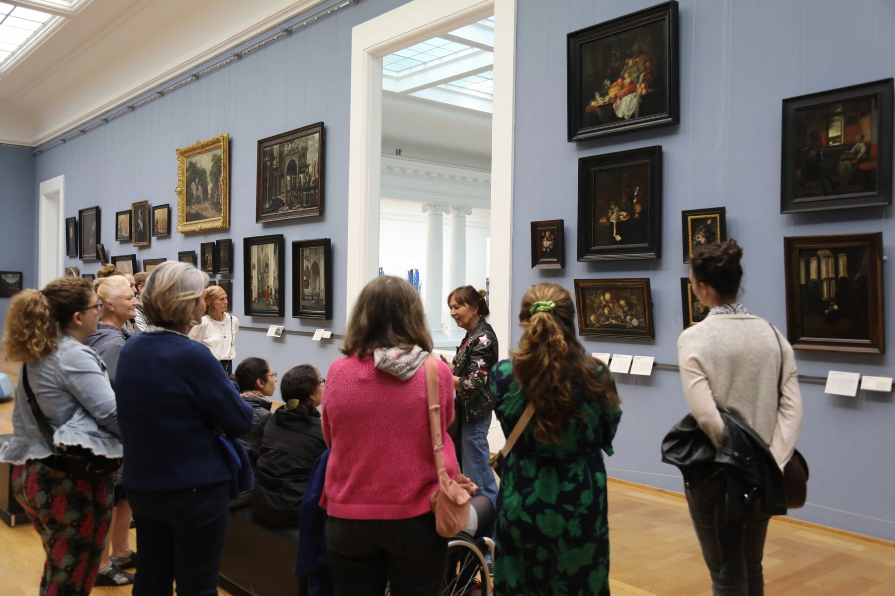 Pascaline Bonnave razgovara sa sudionicima u Palais des Beaux-Arts u Lilleu. Okupljeni su oko zida punog slika tamnih boja.