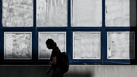 Getty Images Žena prolazi pored prozora škole koji su prekriveni bijelom kredom
